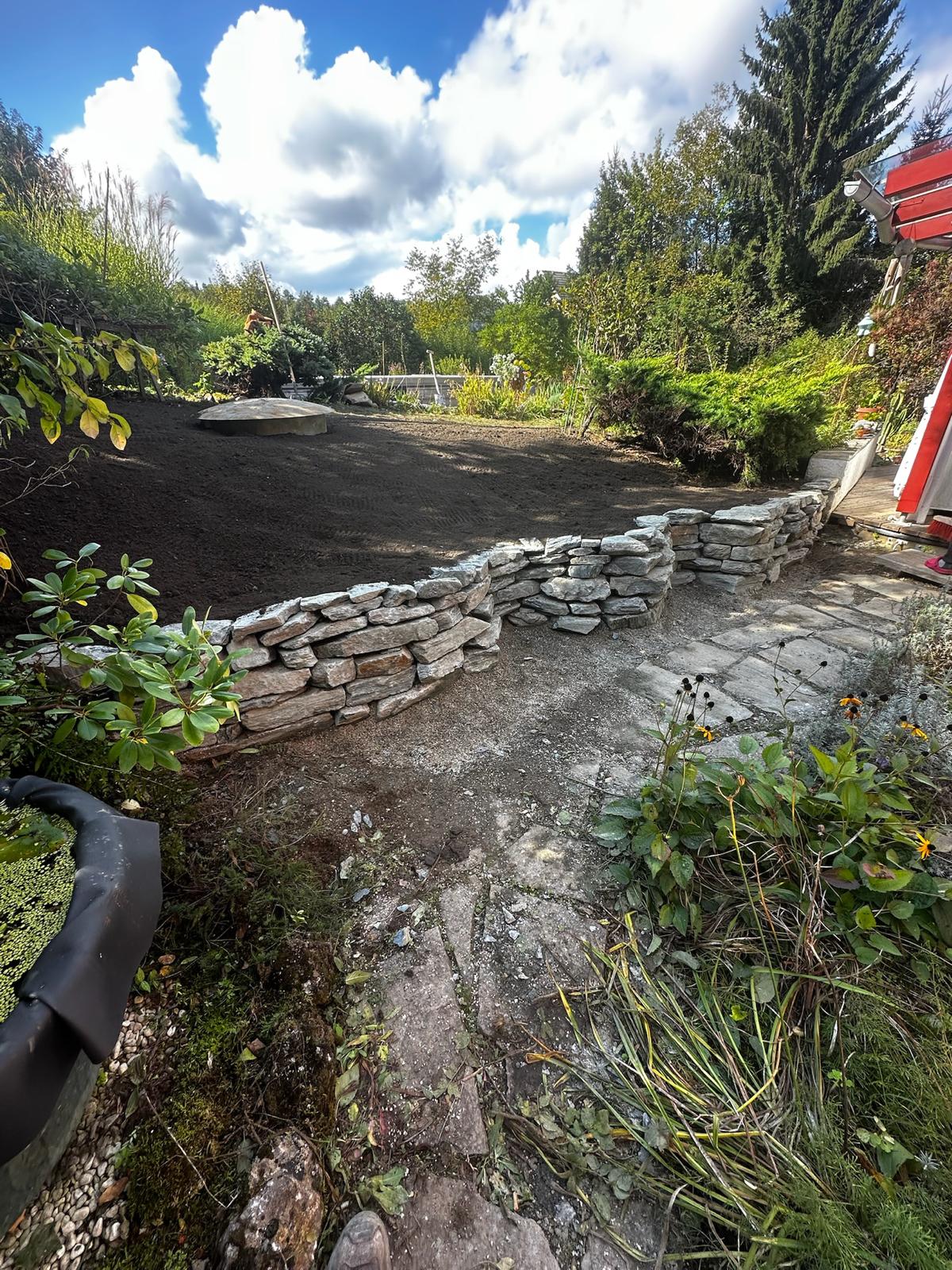 Neu gestaltete Gartenfläche mit Natursteinmauer